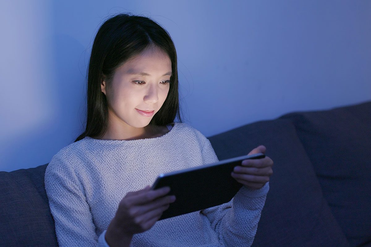 Lady using iPad on a sofa at night