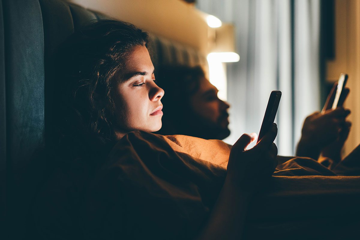 Couple with Smartphones in Their Bed